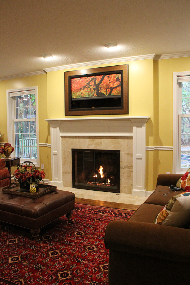 Example of a large classic enclosed medium tone wood floor family room design in Other with yellow walls, a standard fireplace, a wood fireplace surround and a concealed tv