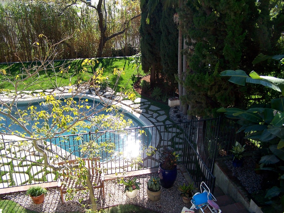 This is an example of a mid-sized traditional backyard custom-shaped lap pool in Los Angeles with concrete pavers.