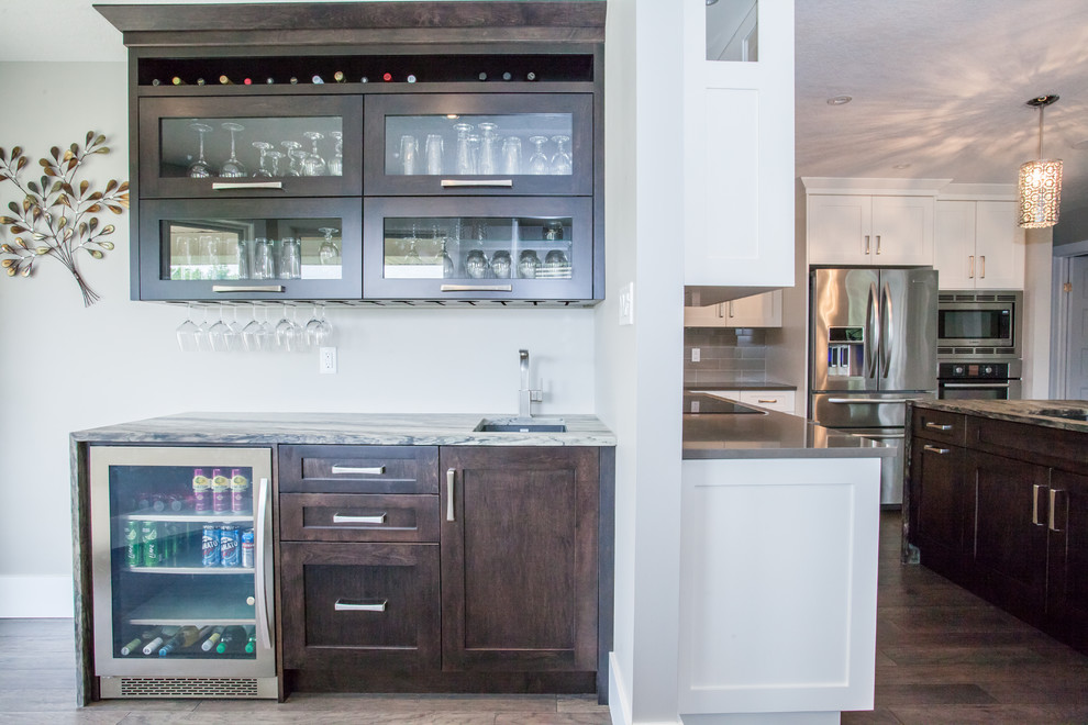 Inspiration for a mid-sized traditional single-wall wet bar in Toronto with an undermount sink, recessed-panel cabinets, dark wood cabinets, granite benchtops, dark hardwood floors, brown floor and multi-coloured benchtop.