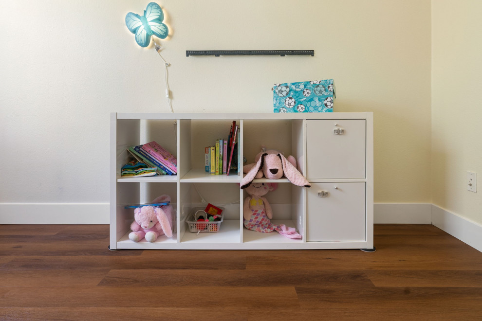 Inredning av ett amerikanskt mellanstort flickrum kombinerat med sovrum och för 4-10-åringar, med beige väggar, vinylgolv och brunt golv