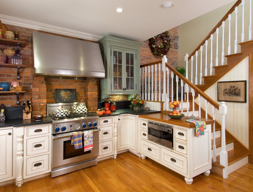 Photo of a small traditional u-shaped eat-in kitchen in Other with beaded inset cabinets, distressed cabinets, stainless steel appliances, light hardwood floors and no island.