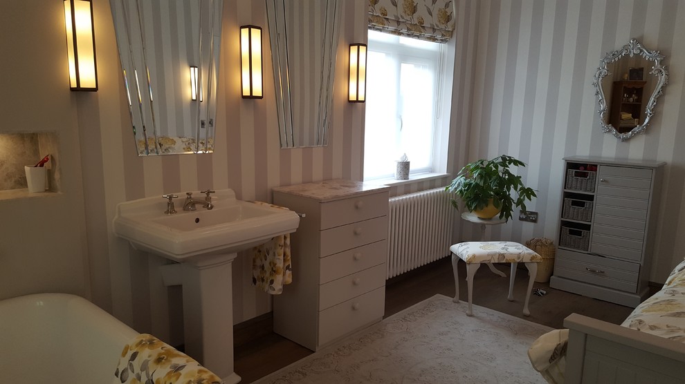 This is an example of a large classic family bathroom in Other with freestanding cabinets, a freestanding bath, an alcove shower, a wall mounted toilet, grey tiles, stone tiles, grey walls, medium hardwood flooring, a pedestal sink, marble worktops, brown floors and a hinged door.