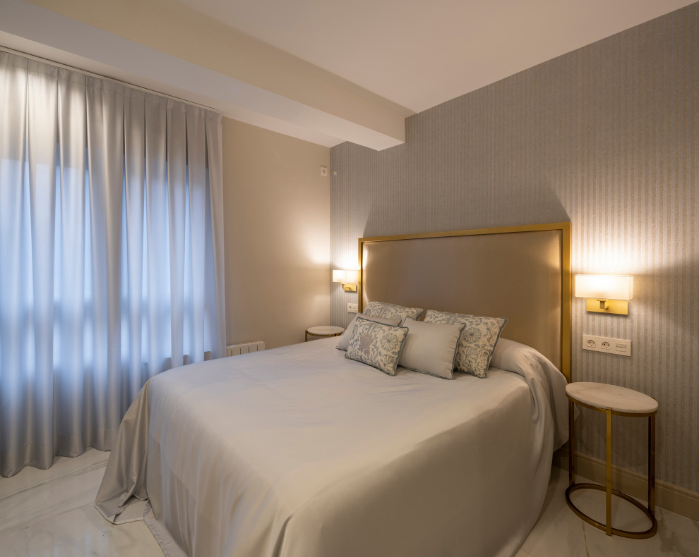 Imagen de dormitorio principal clásico renovado de tamaño medio con paredes beige, suelo de mármol, suelo blanco y papel pintado