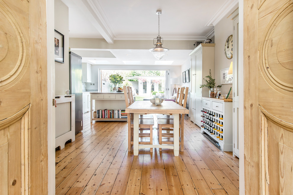This is an example of a mid-sized transitional kitchen/dining combo in London with beige walls and medium hardwood floors.
