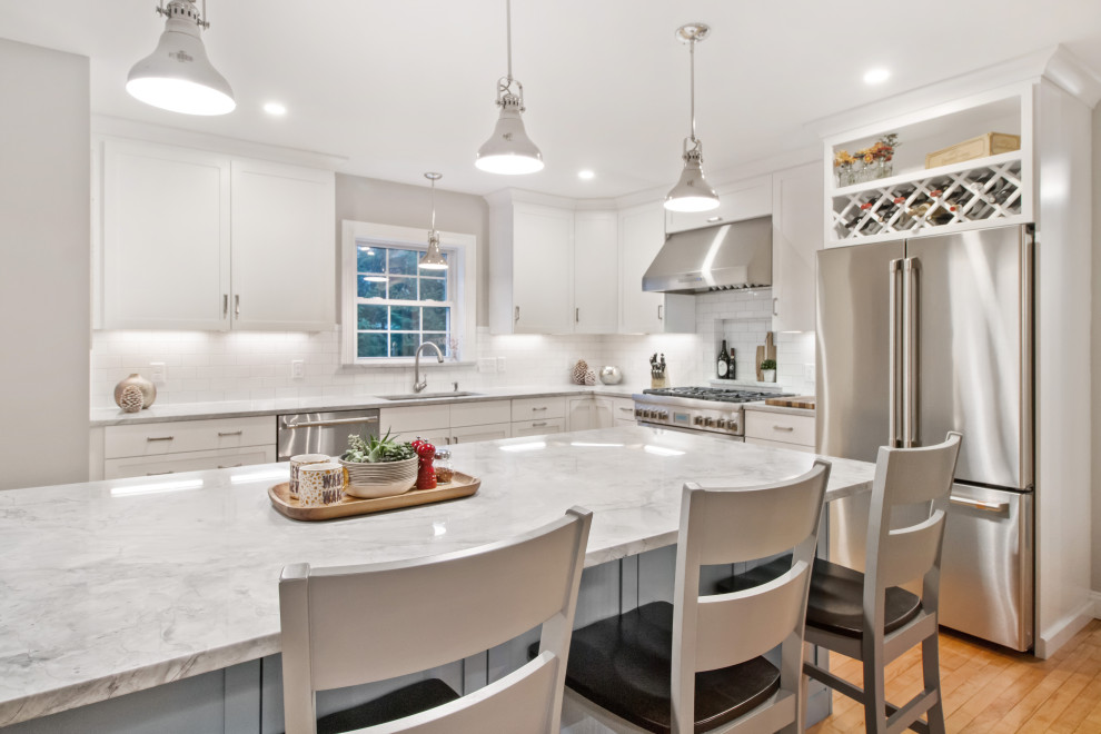 Immagine di una grande cucina stile marinaro con paraspruzzi bianco, paraspruzzi con piastrelle diamantate, elettrodomestici in acciaio inossidabile, pavimento in legno massello medio, pavimento arancione e top bianco