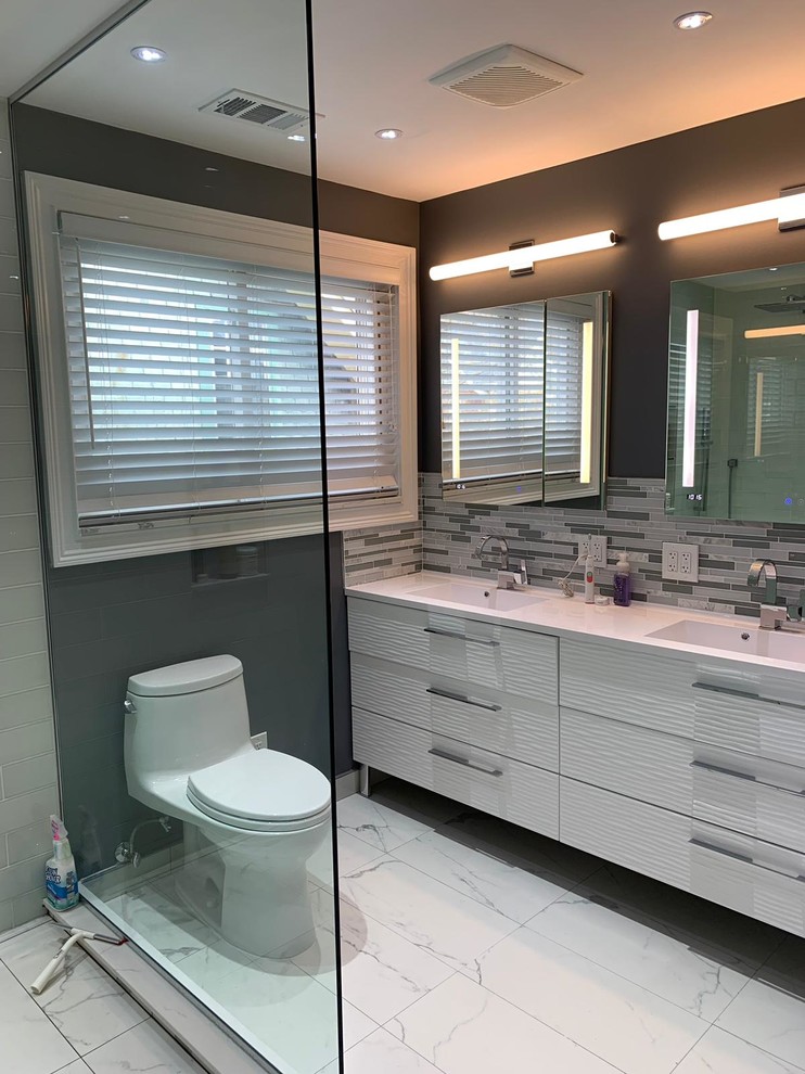 Large modern master bathroom in New York with a freestanding tub, an open shower, a one-piece toilet, white tile, porcelain tile, porcelain floors, a wall-mount sink, white floor, an open shower and white benchtops.