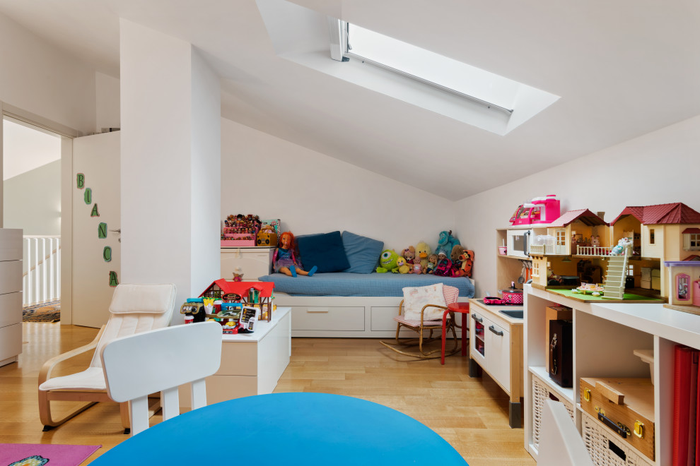 Inspiration for a small modern kids' playroom for kids 4-10 years old and girls in Milan with white walls and light hardwood floors.