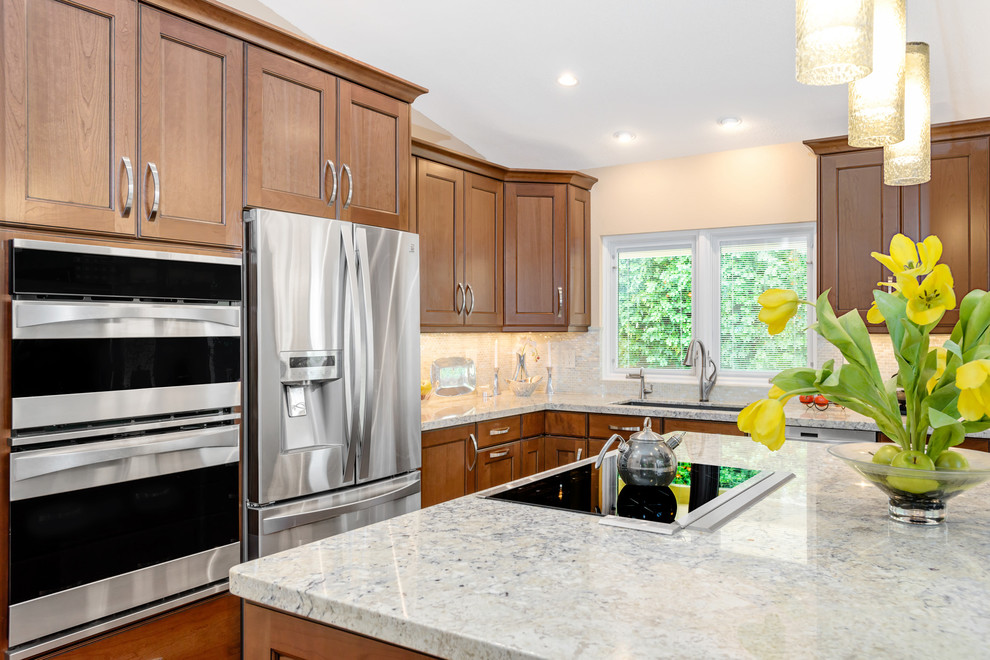 Kitchen - mid-sized transitional l-shaped light wood floor kitchen idea in Phoenix with an undermount sink, medium tone wood cabinets, beige backsplash, stainless steel appliances, an island, flat-panel cabinets, quartz countertops and glass tile backsplash