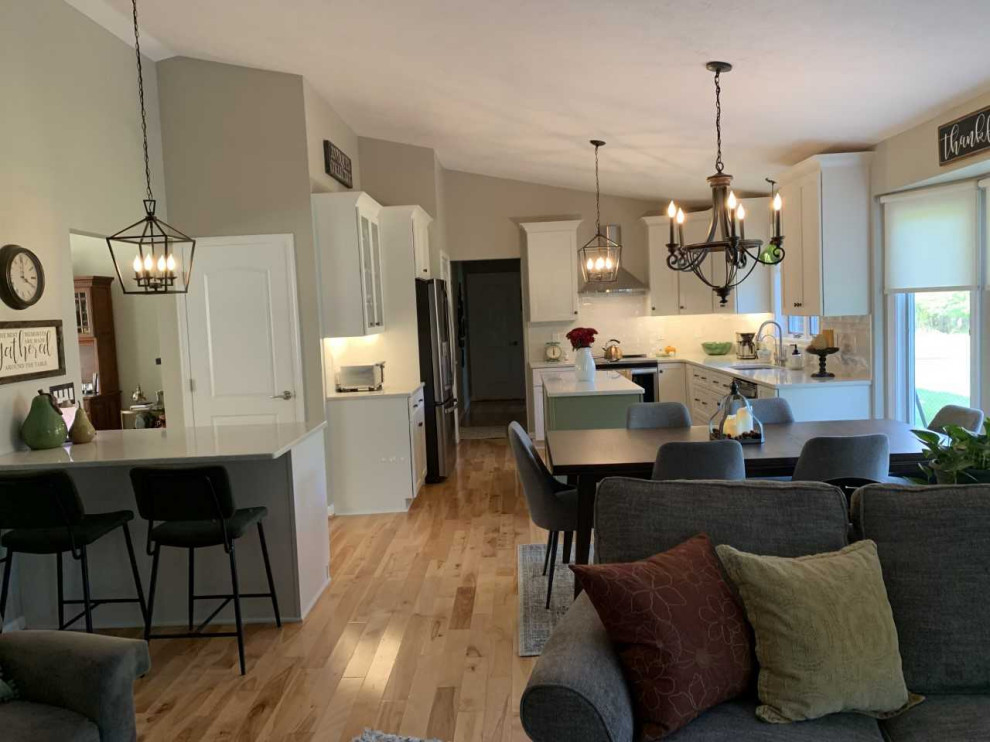 Inspiration for a mid-sized transitional l-shaped light wood floor eat-in kitchen remodel in Baltimore with an undermount sink, shaker cabinets, green cabinets, quartz countertops, white backsplash, subway tile backsplash, stainless steel appliances, an island and multicolored countertops