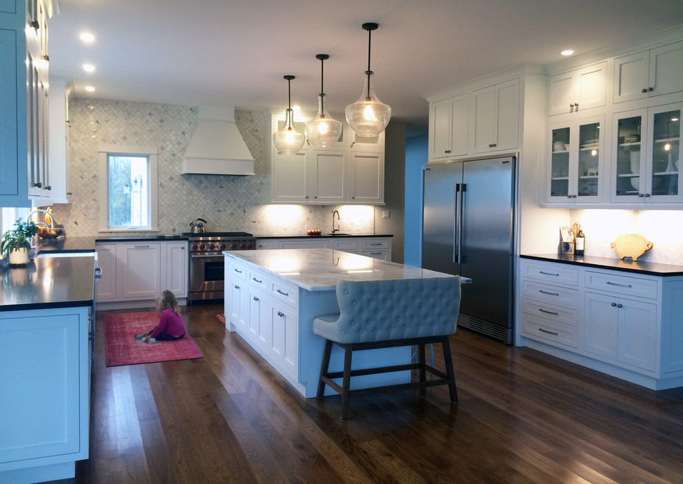 Large transitional u-shaped kitchen pantry photo with a farmhouse sink, recessed-panel cabinets, white cabinets, quartzite countertops, stainless steel appliances, an island and black countertops