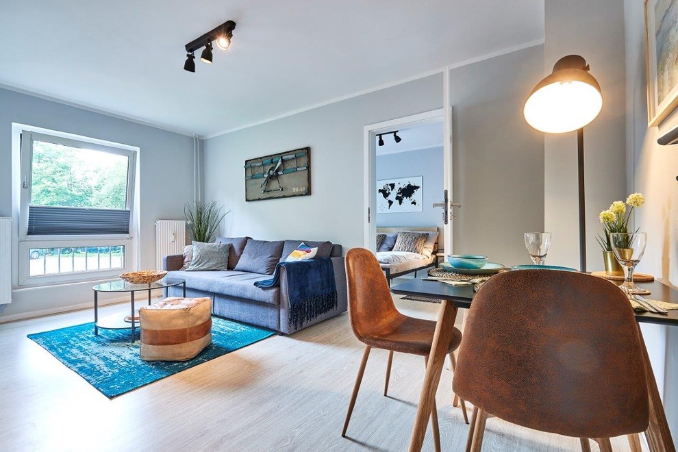 Mid-sized beach style open concept living room in Hamburg with grey walls, light hardwood floors, no fireplace and grey floor.