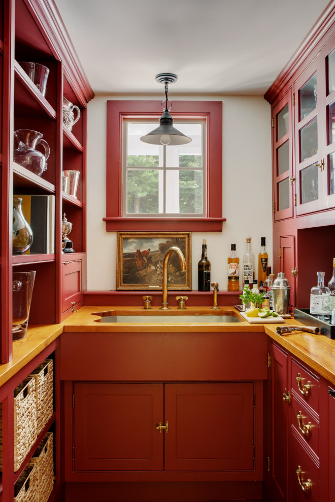 This is an example of a traditional u-shaped wet bar in Boston with an undermount sink, beaded inset cabinets, red cabinets, wood benchtops and brown benchtop.