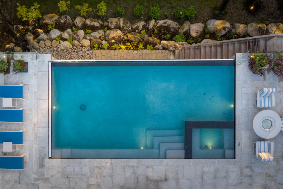 Pool landscaping - mid-sized transitional backyard stone and rectangular infinity pool landscaping idea in Toronto