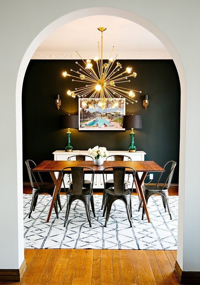This is an example of a mid-sized midcentury dining room in Los Angeles with black walls, medium hardwood floors, no fireplace and brown floor.