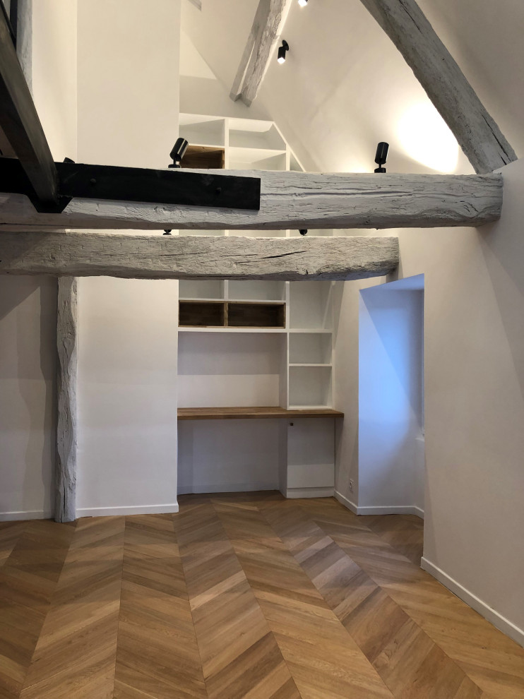 Foto de despacho minimalista pequeño con biblioteca, paredes blancas, suelo de madera en tonos medios y escritorio empotrado