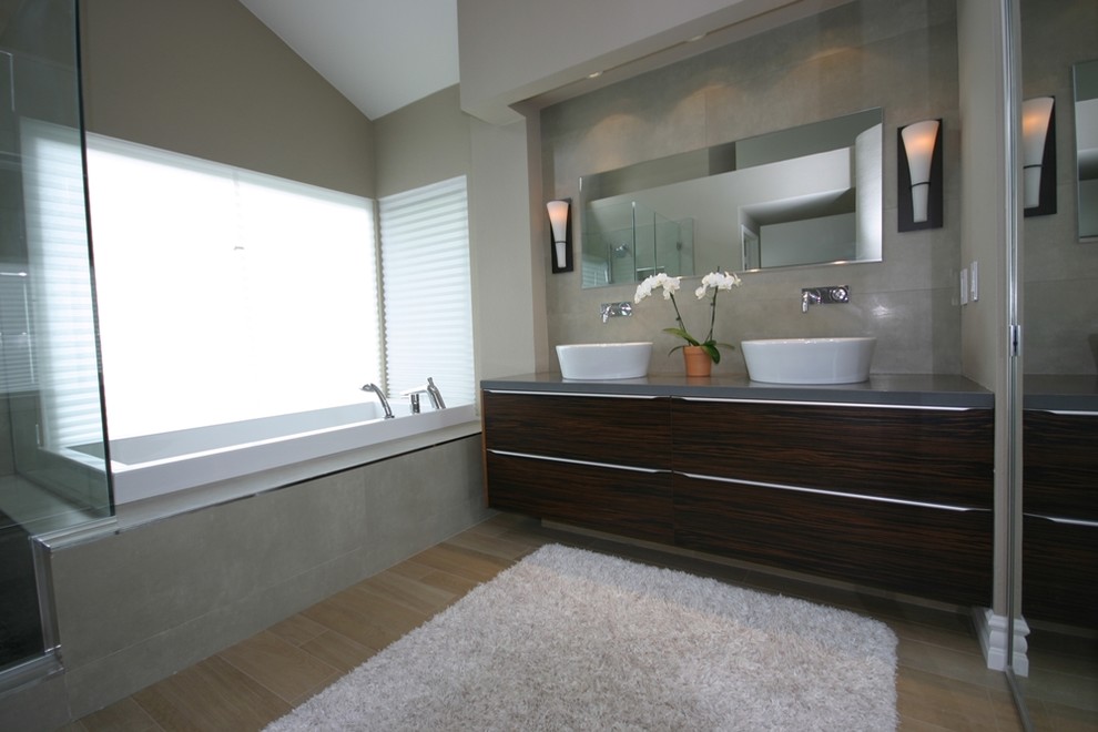 Large modern master bathroom in Orange County with flat-panel cabinets, black cabinets, a corner tub, a corner shower, beige walls, porcelain floors, a vessel sink and solid surface benchtops.