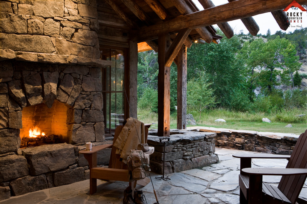 Photo of a mid-sized country side yard patio in Other with a fire feature, natural stone pavers and a roof extension.