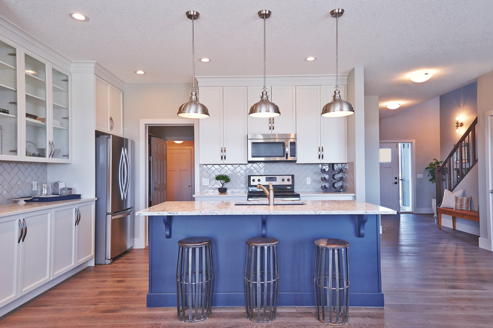 Eat-in kitchen - transitional l-shaped medium tone wood floor eat-in kitchen idea in Calgary with a double-bowl sink, shaker cabinets, blue cabinets, quartzite countertops, gray backsplash, ceramic backsplash, stainless steel appliances and an island