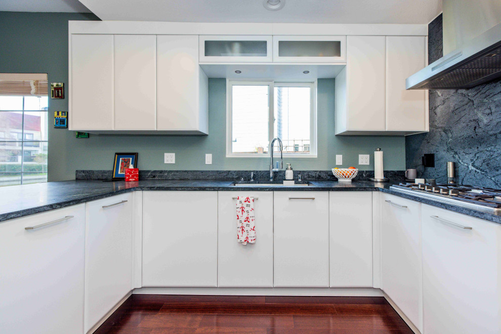 Design ideas for a mid-sized contemporary u-shaped kitchen pantry with an undermount sink, flat-panel cabinets, white cabinets, solid surface benchtops, black splashback, engineered quartz splashback, stainless steel appliances, dark hardwood floors, a peninsula, brown floor, black benchtop and recessed.