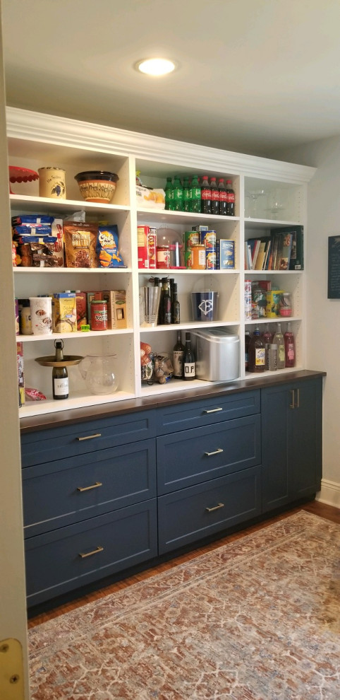 Photo of a small traditional gender-neutral built-in wardrobe in New York with recessed-panel cabinets, blue cabinets, dark hardwood floors and brown floor.