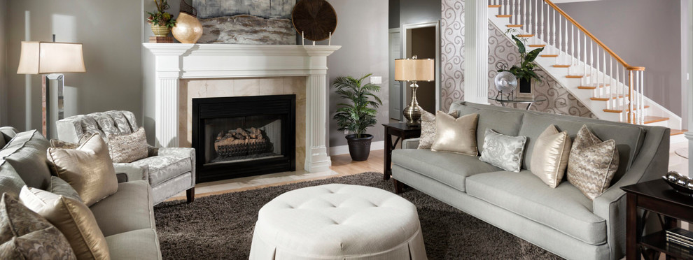 Inspiration for a mid-sized traditional formal enclosed living room in Miami with grey walls, light hardwood floors, a standard fireplace, a tile fireplace surround, no tv and brown floor.