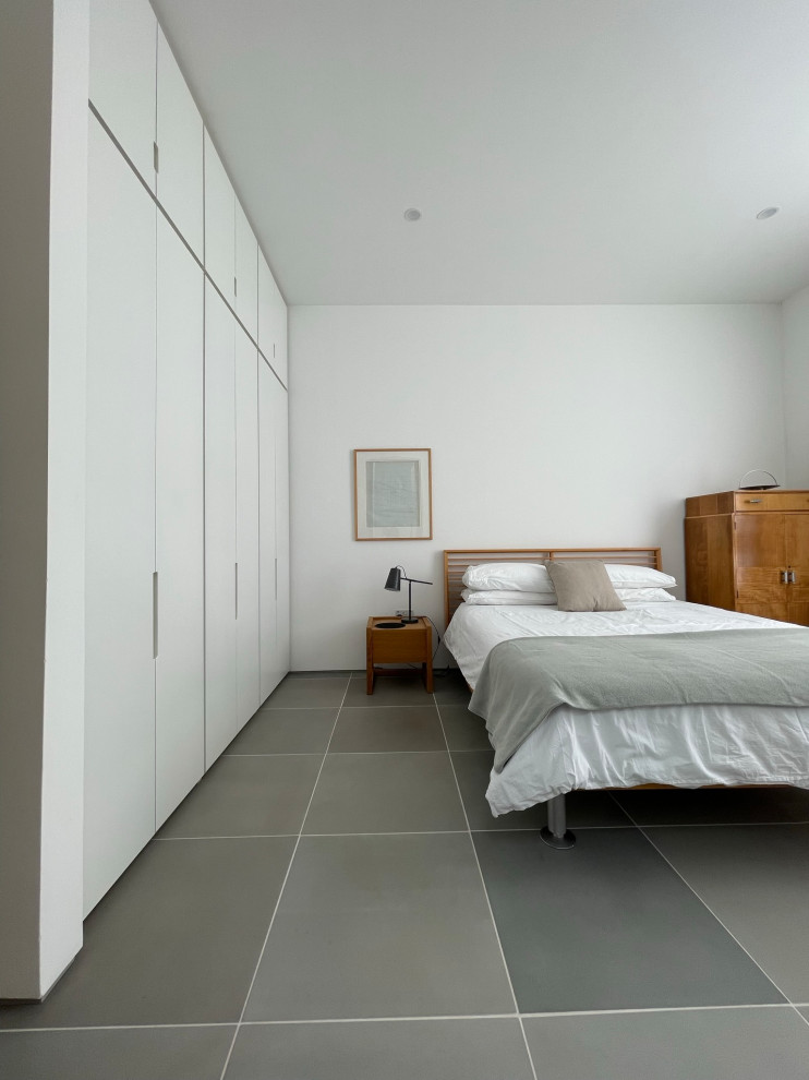 Inspiration pour une chambre d'amis design de taille moyenne avec un mur blanc, un sol en carrelage de céramique et un sol gris.
