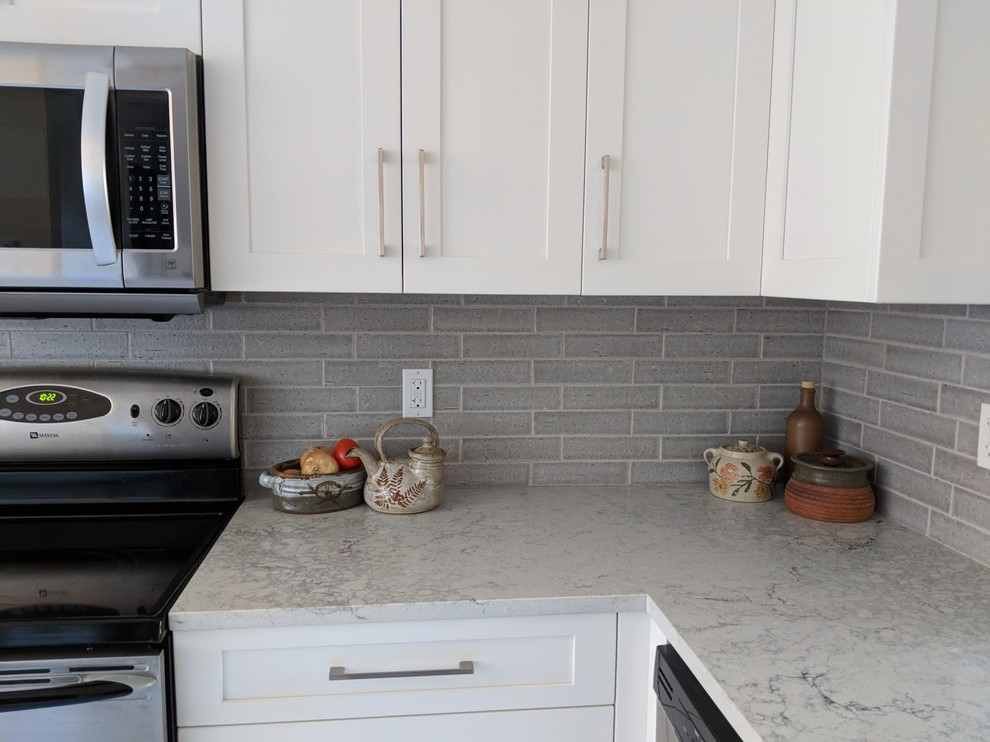 Example of a small transitional u-shaped vinyl floor and beige floor eat-in kitchen design in Vancouver with a single-bowl sink, shaker cabinets, white cabinets, quartz countertops, gray backsplash, ceramic backsplash, stainless steel appliances, no island and gray countertops