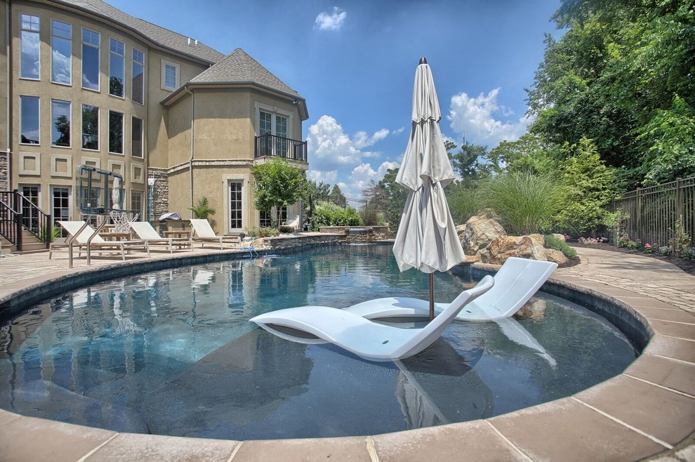 Photo of a large contemporary backyard kidney-shaped pool in Philadelphia with a hot tub and concrete pavers.