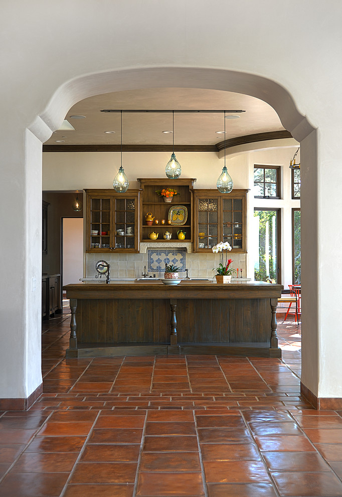 Inspiration for a large mediterranean l-shaped open plan kitchen in San Francisco with an undermount sink, recessed-panel cabinets, dark wood cabinets, multi-coloured splashback, ceramic splashback, stainless steel appliances, terra-cotta floors, with island and red floor.