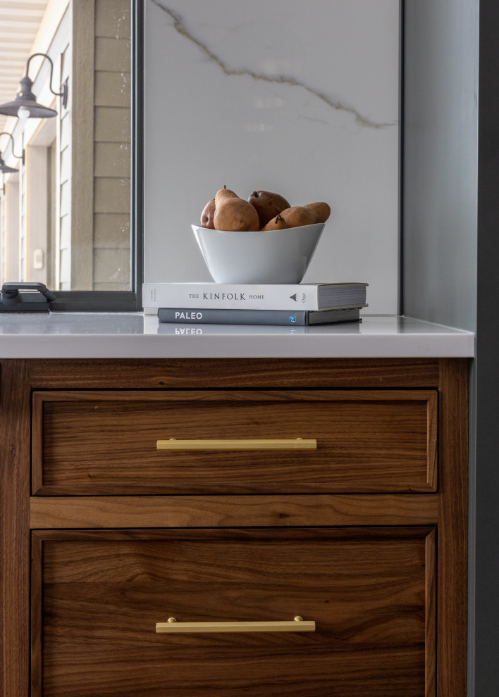 Example of a mid-sized transitional l-shaped light wood floor and brown floor eat-in kitchen design with a farmhouse sink, shaker cabinets, blue cabinets, quartz countertops, white backsplash, quartz backsplash, black appliances, an island and white countertops