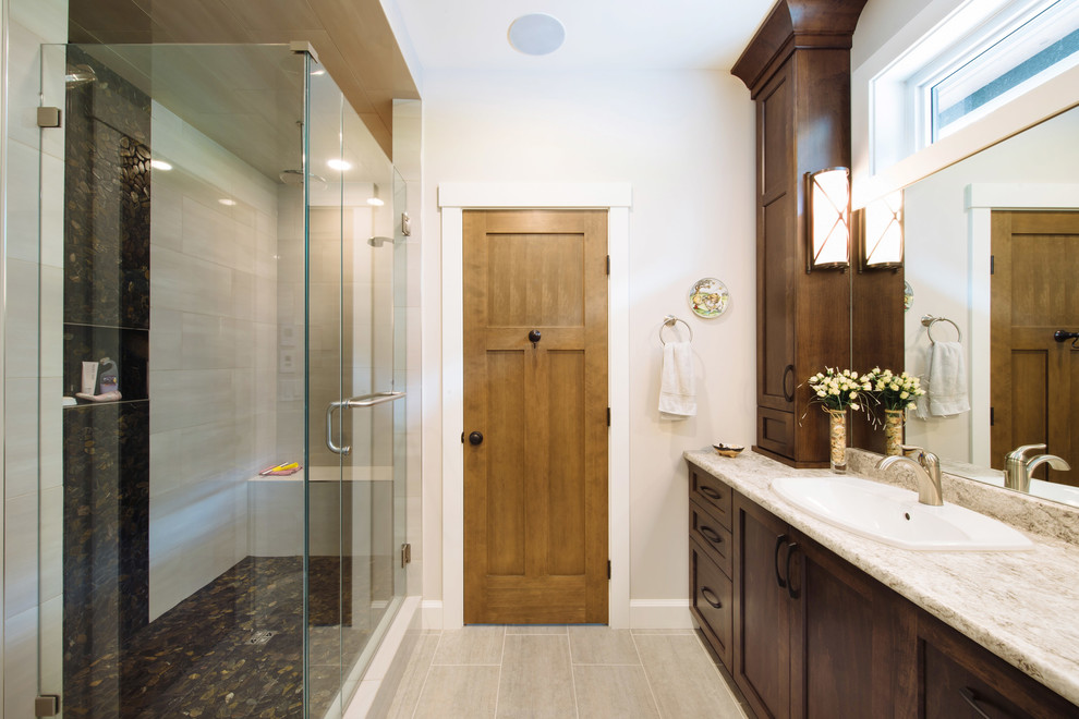 This is an example of a mid-sized traditional master bathroom in Vancouver with shaker cabinets, a double shower, beige tile, black tile, granite benchtops, dark wood cabinets, pebble tile, beige walls, vinyl floors and a drop-in sink.