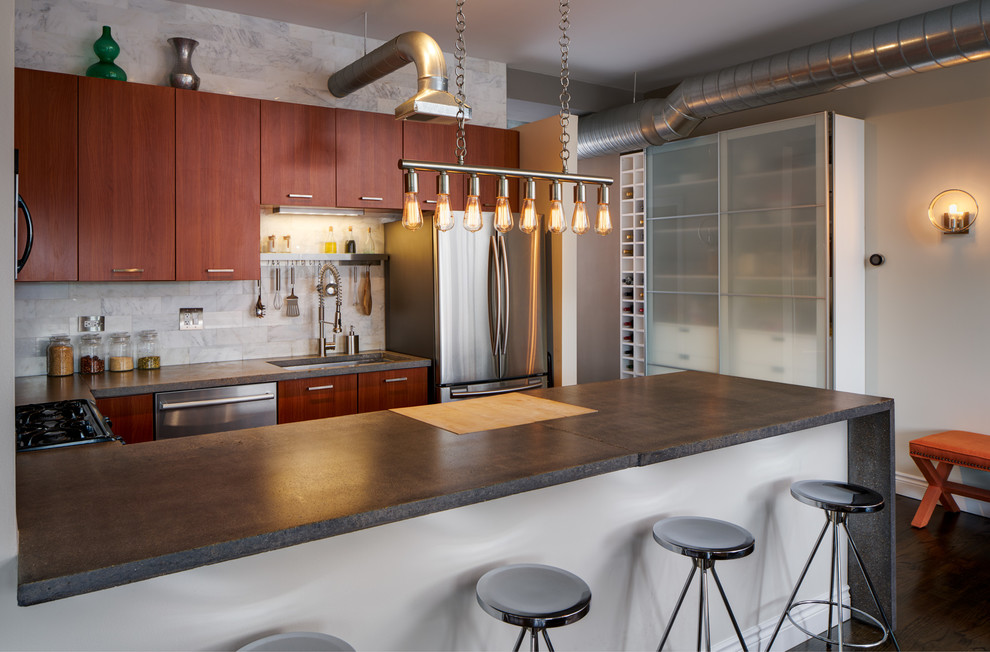 Inspiration for a large industrial u-shaped eat-in kitchen in Chicago with an undermount sink, flat-panel cabinets, red cabinets, concrete benchtops, grey splashback, marble splashback, stainless steel appliances, dark hardwood floors, a peninsula and brown floor.