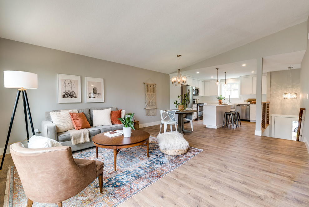 Mid-sized modern open concept family room in Portland with grey walls, laminate floors, a hanging fireplace, a wood fireplace surround, a wall-mounted tv and brown floor.
