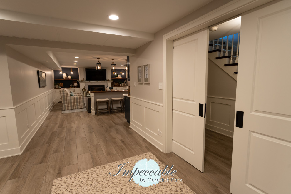 Inspiration for an expansive transitional look-out basement in Chicago with a game room, grey walls, porcelain floors, a standard fireplace, a brick fireplace surround, brown floor and decorative wall panelling.
