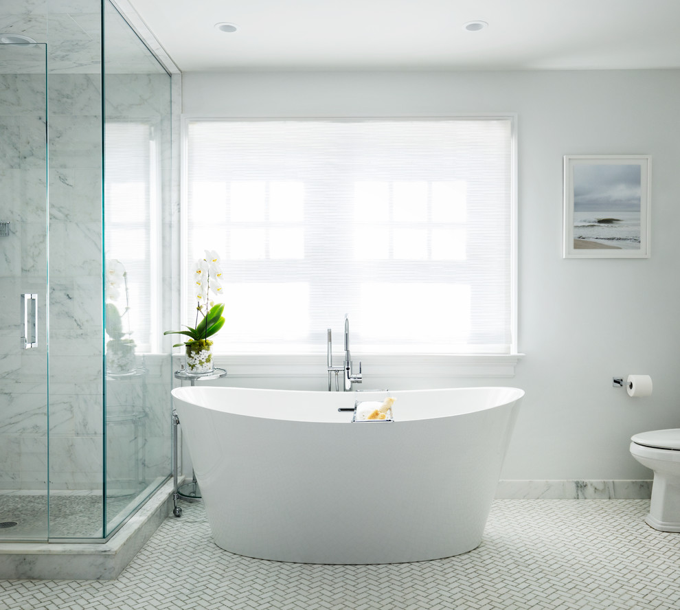 Photo of a large contemporary master bathroom in New York with a freestanding tub, an open shower, a two-piece toilet, white walls, marble floors, white floor and a hinged shower door.