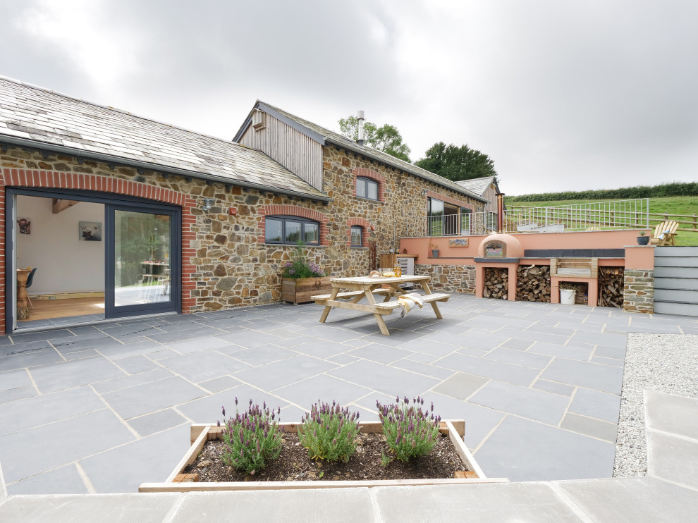 Inspiration for a country backyard patio in Cornwall with natural stone pavers.