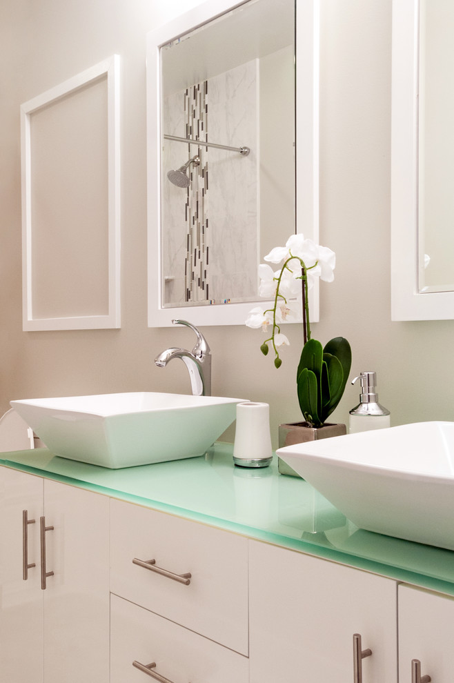 Mid-sized modern master bathroom in DC Metro with flat-panel cabinets, white cabinets, a drop-in tub, a shower/bathtub combo, a one-piece toilet, black and white tile, mosaic tile, beige walls, a vessel sink, glass benchtops and marble floors.