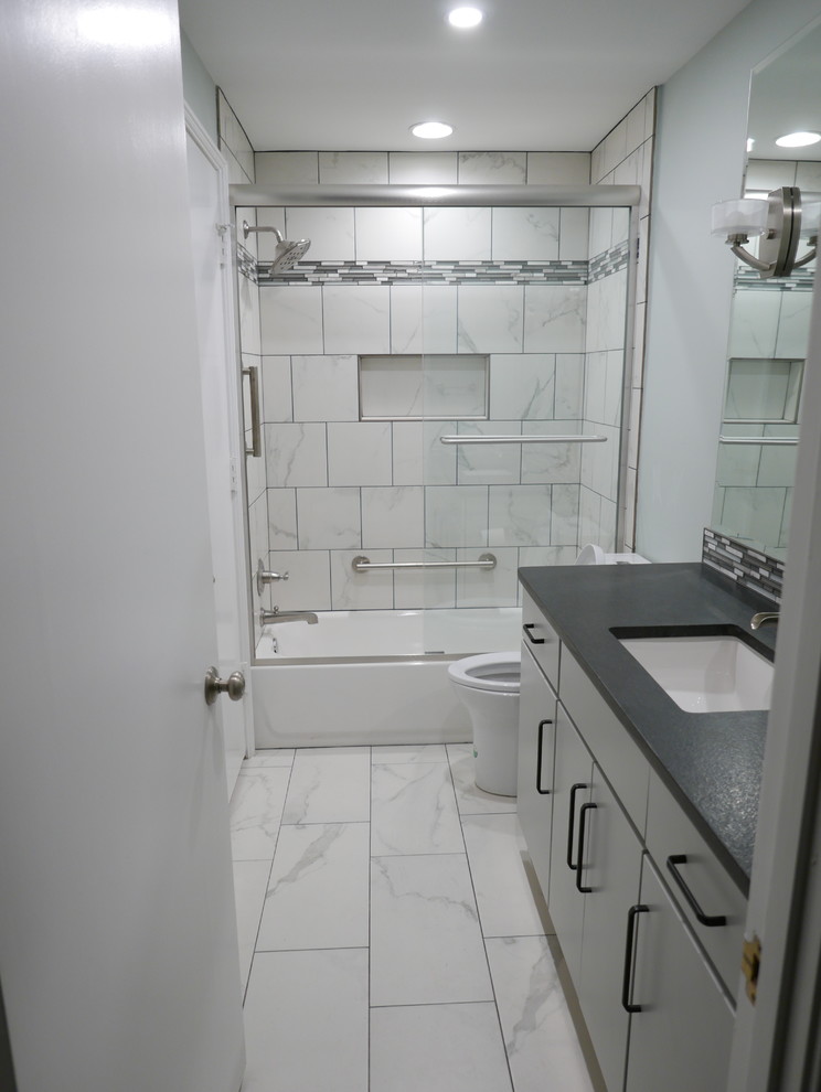 Mid-sized contemporary kids bathroom in Other with flat-panel cabinets, grey cabinets, an alcove tub, a shower/bathtub combo, a two-piece toilet, white tile, porcelain tile, green walls, porcelain floors, an undermount sink, granite benchtops, white floor, a sliding shower screen and black benchtops.