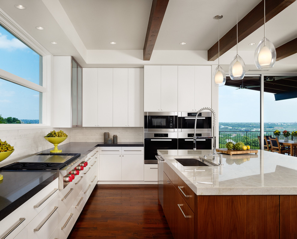 Photo of a contemporary l-shaped kitchen in Austin with an undermount sink, flat-panel cabinets, white cabinets, white splashback and stainless steel appliances.