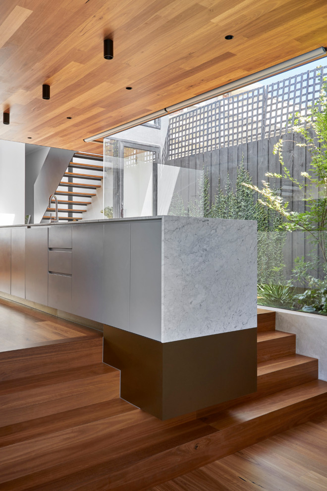 Photo of a mid-sized contemporary galley open plan kitchen in Melbourne with an undermount sink, grey cabinets, marble benchtops, medium hardwood floors, with island, timber and white benchtop.