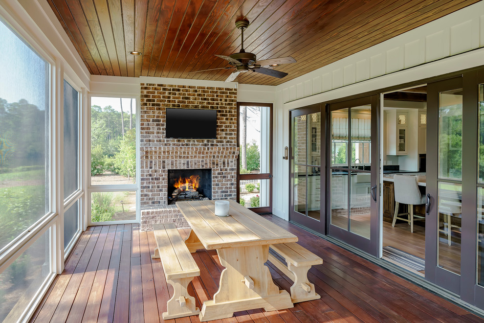 This is an example of a mid-sized country sunroom in Atlanta with dark hardwood floors, a standard fireplace, a brick fireplace surround, a standard ceiling and brown floor.