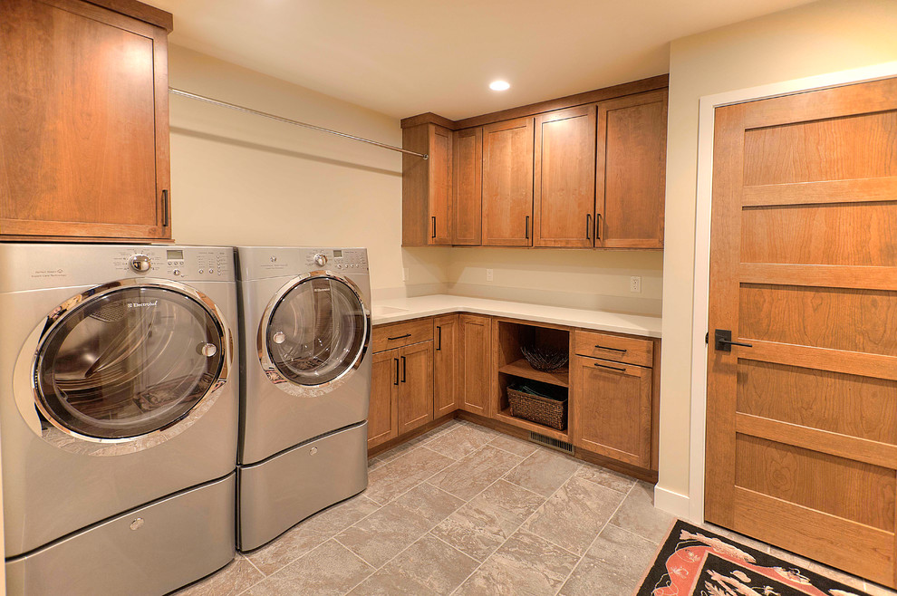 Design ideas for a mid-sized transitional l-shaped utility room in Other with an integrated sink, shaker cabinets, medium wood cabinets, solid surface benchtops, beige walls, ceramic floors and a side-by-side washer and dryer.