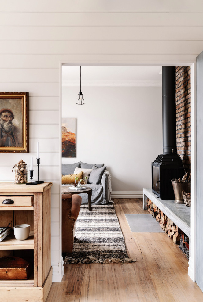 Kleine Maritime Wohnküche mit weißer Wandfarbe, hellem Holzboden, Kamin, Kaminumrandung aus Beton und Ziegelwänden in Melbourne