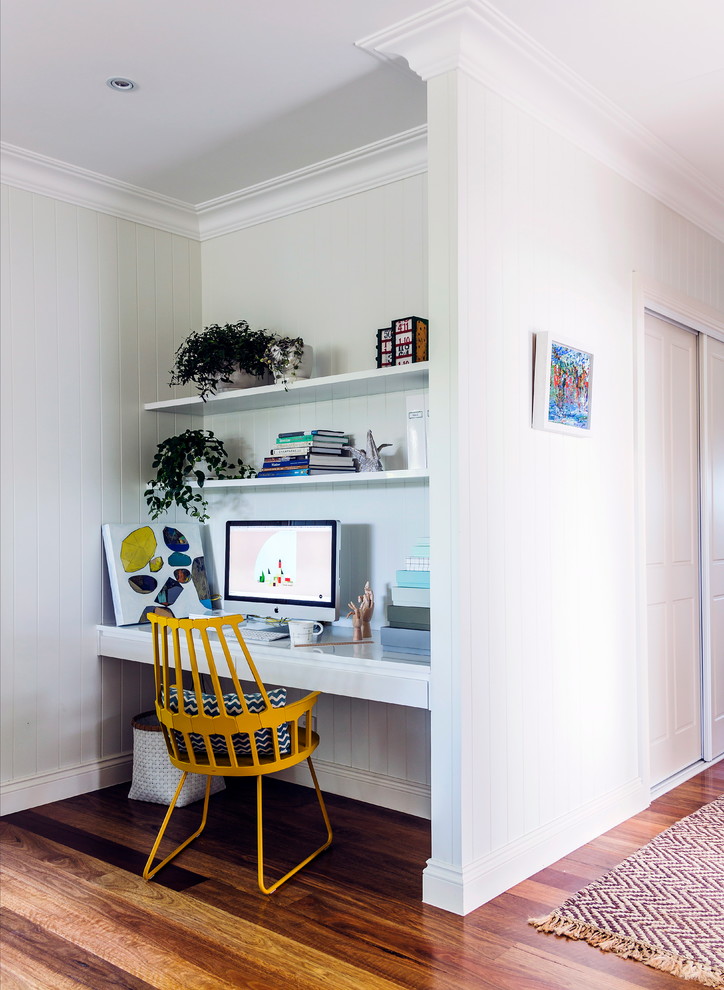 Beach style study room in Melbourne with medium hardwood floors, a built-in desk and white walls.