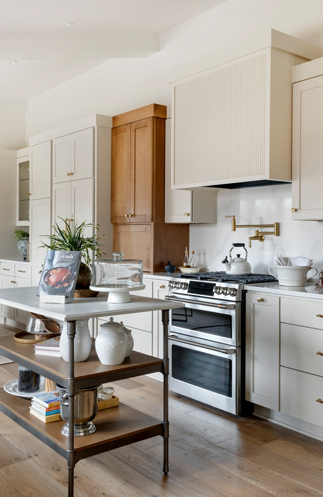 Mid-sized transitional galley medium tone wood floor, brown floor and vaulted ceiling eat-in kitchen photo in Minneapolis with an undermount sink, shaker cabinets, quartz countertops, white backsplash, subway tile backsplash, stainless steel appliances, an island and white countertops