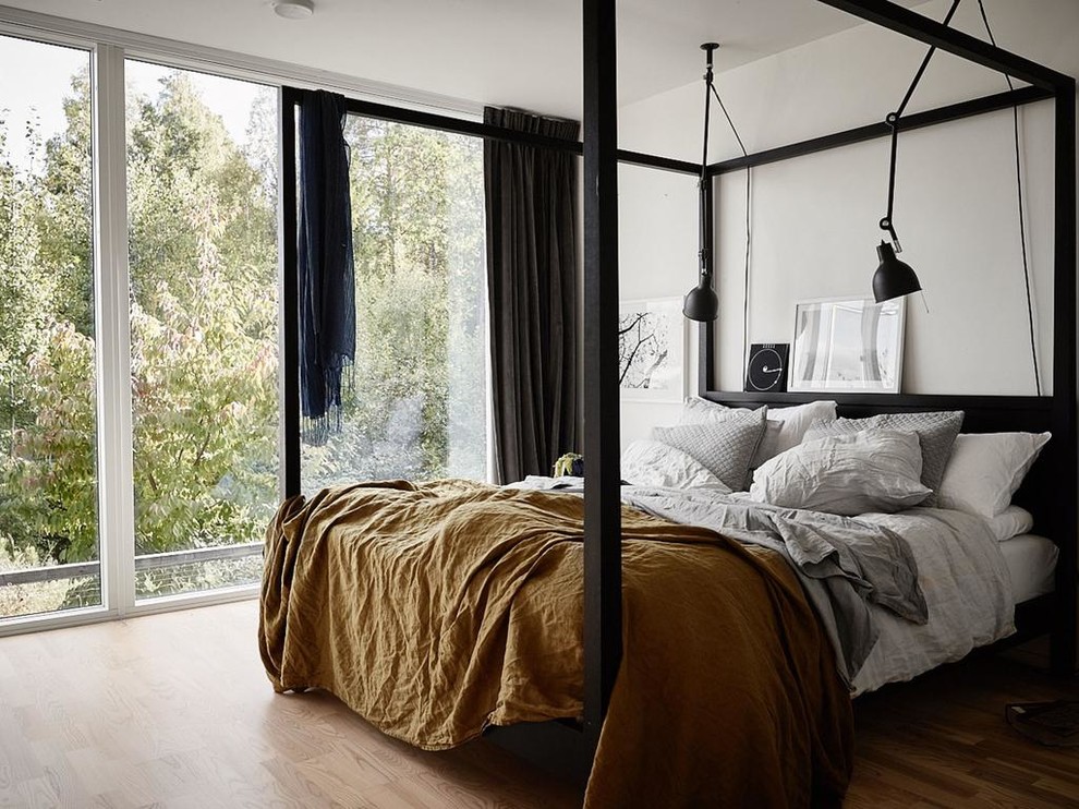 This is an example of a mid-sized scandinavian master bedroom in Stockholm with white walls and light hardwood floors.