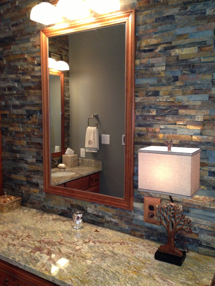 Example of a mountain style drop-in bathtub design in St Louis with raised-panel cabinets, distressed cabinets and granite countertops