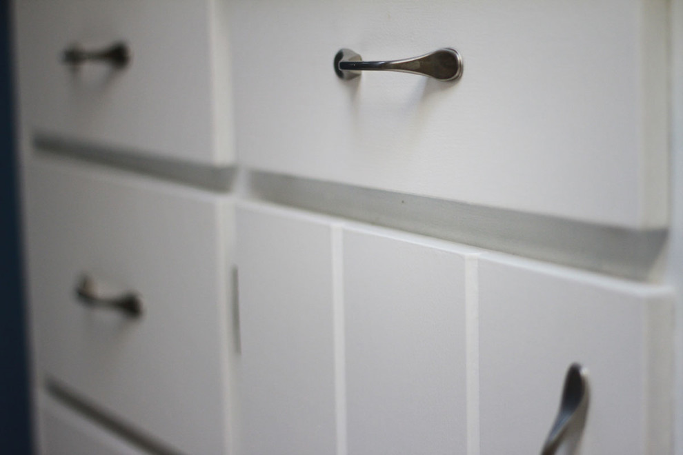 Example of a mid-sized transitional l-shaped linoleum floor enclosed kitchen design in Seattle with an undermount sink, flat-panel cabinets, white cabinets, solid surface countertops, white backsplash, subway tile backsplash, stainless steel appliances, blue walls and no island