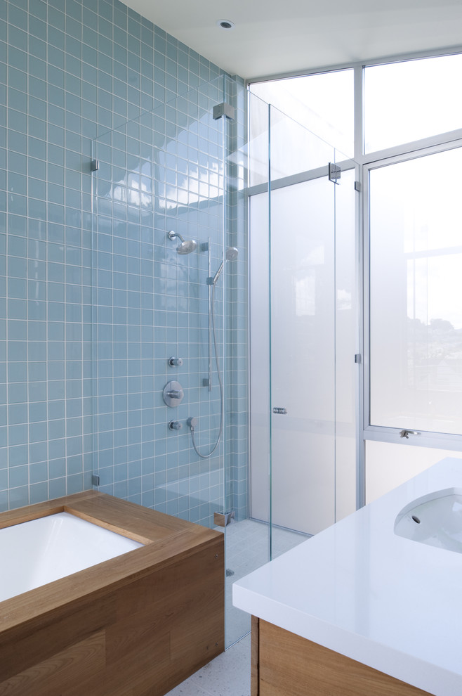 Photo of a modern bathroom in San Francisco with medium wood cabinets, an undermount tub, an alcove shower and blue tile.