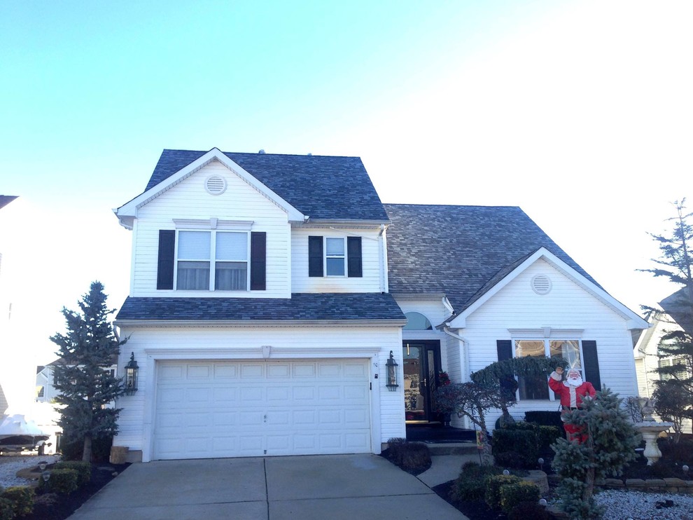 Large traditional white exterior in New York with vinyl siding and a gambrel roof.